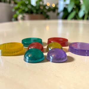 Een sfeerimpressie van handgemaakte Pure Color Tachyon koepel (3,5 cm) en oplaadschijf (6cm) die op een houten tafel liggen, met een subtiele visualisatie van een zacht energetisch torus-veld dat de creaties omringt.